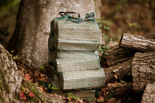 Load image into Gallery viewer, Net sack of firewood in a woodland.